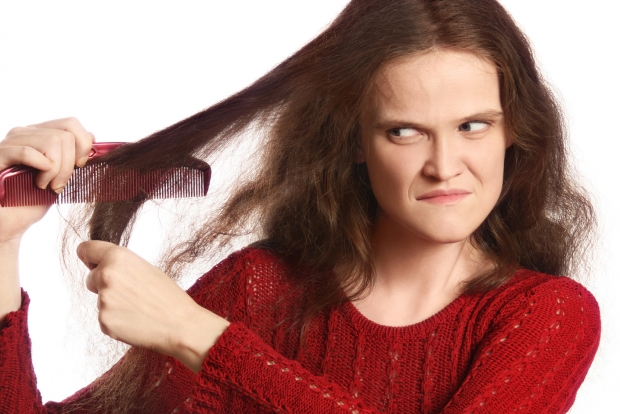 Combing hair. Angry woman combing her long unmanageable unruly problematic hair.