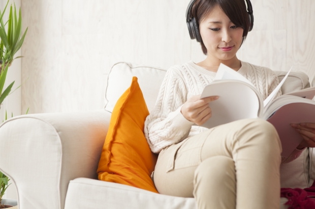 Woman is reading a magazine while listening to music