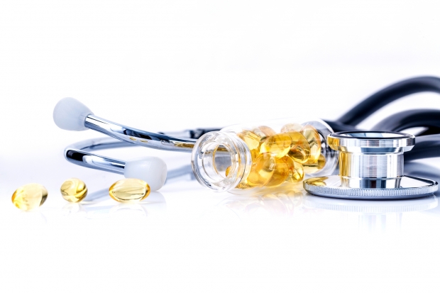 Fish oil capsules in bottle with stethoscope isolate on white background.