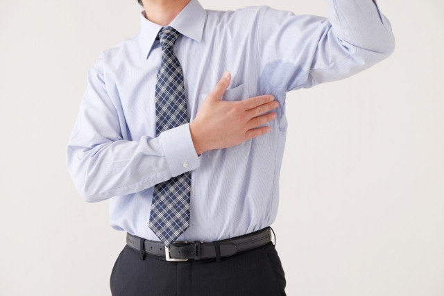 汗じみのシャツを触る男性